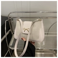 Nahaufnahme einer weißen Schultertasche mit goldener Schleifenschnalle und Materialmix - Weiß