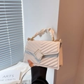 Elegant white quilted crossbody bag with golden buckle and ruffled top handle for women - White