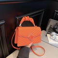 Bright orange quilted handbag with V-stitch pattern and unique twisted handle for women - Orange