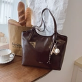 Bolso tote marrón oscuro de cuero sintético con colgante de béisbol en una mesa - Café Con Colgante