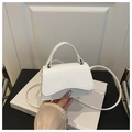 Detailed view of white crocodile pattern crossbody bag with wavy flap on decorative books - White