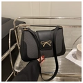 Detalle de bolso de hombro en cuero negro y tela con cierre de lazo dorado elegante - Negro