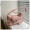 Detail of pink pleated leather bag featuring a decorative bow and metallic centerpiece - Pink