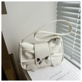 Detail of white shoulder bag featuring a decorative bow knot and silver metallic bow buckle - White