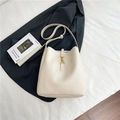 Secchiello in pelle bianco crema con chiusura dorata su lenzuola bianche e rivista - Bianco Sporco