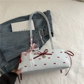 Hellblaue Schultertasche mit Schleife, roten Punkten und Spitzenbändern in Lifestyle-Szene - Blau