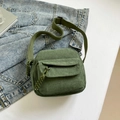 Dark green corduroy crossbody bag with woven zipper pull on denim jacket background - Green