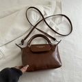 Chic brown dumpling crossbody bag with adjustable strap and top handle design - Tan