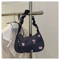 Detail of denim bow print handbag with pleated cloud handle on a display stand - Black