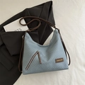 Blue and white woven crossbody bag with brown leather strap on a stylish black blazer - Blue