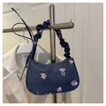 Close-up of blue denim underarm bag with pink floral patterns and pleated shoulder strap - Dark Blue