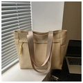 Detail of beige straw tote bag featuring woven texture and decorative yellow tassels - Khaki