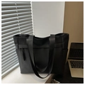 Close-up of black tote bag featuring vertical woven texture and wide shoulder straps - Black