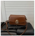 Detailed shot of brown flap crossbody bag with golden arched buckle on black books - Dark Brown