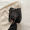 Fashionable black sequin bucket bag with silver chain strap on white blazer - Black