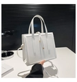 Gros plan du sac cabas en cuir blanc avec détails dorés et cordon de serrage décoratif - Blanc
