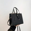 Minimalist black matte leather tote bag featuring tassel detail and adjustable strap - Black