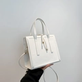 White minimalist PU leather crossbody bag with dual handles and gold metallic pendant - White