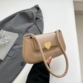 Beige underarm bag with gold heart clasp and padded strap held against a grey suit - Khaki