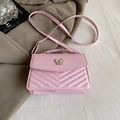 Close-up of pink V-quilted small square bag with metal butterfly and stylish accessories - Pink