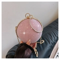 Detailed close-up of pink glitter sphere clutch with gold ring handle and metal chain - Pink