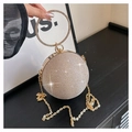 Macro view of champagne gold spherical evening bag with glitter texture and ring handle - Gold