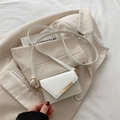 Mini borsa bianca a tracolla con chiusura in metallo dorato e cinturino su blazer beige - Bianco