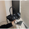 Detail of black pleated bucket bag with bow decoration and slim handle on sunlit background - Black