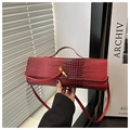Détail d'un sac à main bordeaux avec relief crocodile et fermoir doré élégant - Rouge