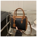 Detalle del bolso de mano bicolor con textura litchi y herrajes de metal dorado - Negro