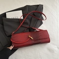 Sac baguette rouge foncé avec motif crocodile et boucle dorée sur fond quadrillé blanc - Rouge