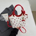White cherry print bucket bag with red handles and 3D cherry charm in a stylish pose - With Pendant / Burgundy