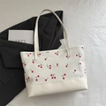 White canvas tote bag featuring all-over red cherry print and reinforced leather base - White
