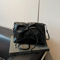 Elegant black faux leather crossbody bag featuring a large decorative bow and soft pleats - Black