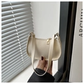 Close-up of cream baguette bag with litchi grain texture and gold zipper details - White