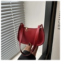 Close-up of red lychee textured leather baguette bag featuring a gold zipper puller - Red