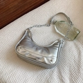 Bolso plateado brillante con correa de cadena sobre tela blanca con relieve - Plateado