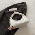 Schicke beige Hobo-Tasche mit geknotetem Griff auf einem grauen Blazer präsentiert - Weiß