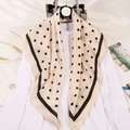 Close-up of beige polka dot silk scarf draped over a white top on a floral hanger - Khaki Polka Dot Style