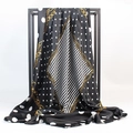 Gros plan d'un foulard élégant en satin noir et blanc avec motifs de chaînes dorées - Noir