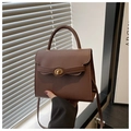 Close-up of brown textured crossbody bag with golden circular twist lock and leather strap - Coffee