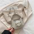 Mini cream faux leather handbag with a large silver metal bow and chain strap - White