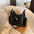 Borsa tote nera lucida vintage con frange e zip metallica su un divano beige - Con Ciondolo / Nero