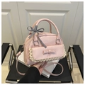 Detail van roze PU-leren handtas met kanten rand en geruite lintdecoratie op het handvat - Roze