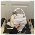 Detailweergave van de witte crossbodytas met kanten randen en een decoratieve strik - Wit