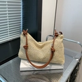 Handwoven straw tote bag with brown leather straps displayed on artistic books - Dark Brown