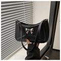 Close-up of black leather underarm bag featuring silver bow detail and 3D geometric stitching - Black