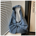 Detailed view of the oversized denim bow and knotted handle on a navy blue tote bag - Blue