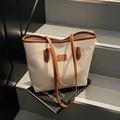 Bolso tote de lona en contraste con bordes de cuero marrón en un fondo de estudio elegante - Marrón