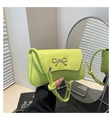 Close-up of light green shoulder bag with silver metal bow and textured PU leather - Green
